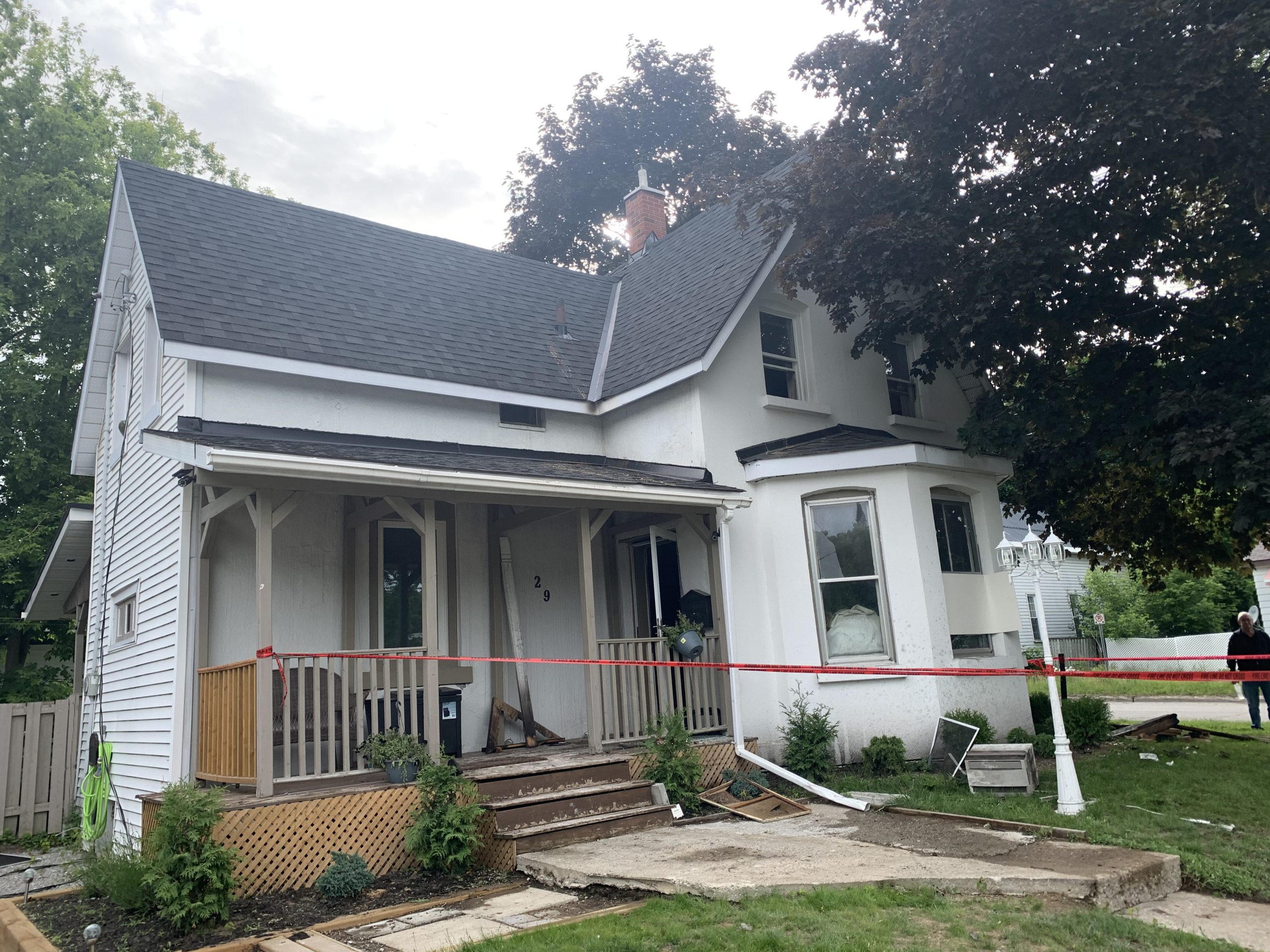 A white fire damaged home condemmed with caution tape